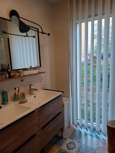 une salle de bain avec un lavabo et une grande fenêtre dans l'établissement Quiet house with wooded garden, à Les Sables-dʼOlonne
