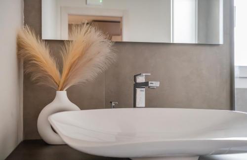 a bathroom with a white tub and a vase with feathers in it at Residence Goldoni6 Suite Apartment in Rimini