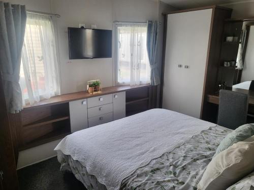 a bedroom with a bed and a desk with a television at The Retreat - Skyline in Prestatyn