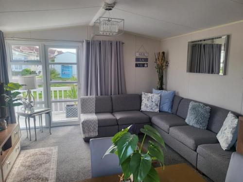 a living room with a gray couch and a window at The Retreat - Skyline in Prestatyn