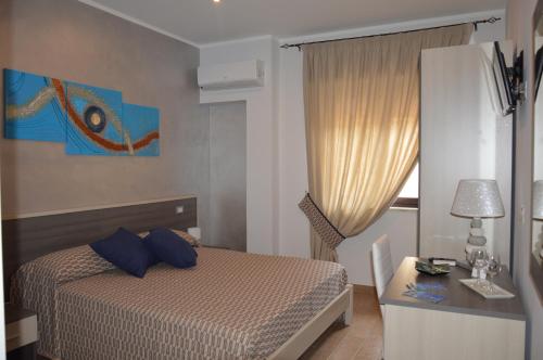 1 dormitorio con cama con almohadas azules y escritorio en La Conchiglia, en Tropea