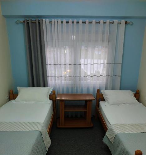 two beds in a room with a window at Solaris Guest House in Shkodër