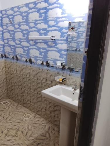 a bathroom with a sink and palm trees on the wall at Neptune house in Puttalam