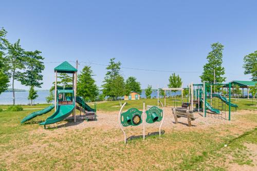 a playground with a bunch of playground equipment in a park at Walk to Manistee Lake Retro Cottage with Fire Pit! in Kalkaska