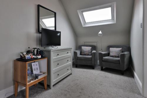a living room with two chairs and a television at Bodnant Guest House in Llandudno