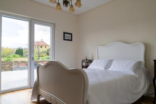 a bedroom with a white bed and a sliding glass door at Casa da Tapada in São João da Pesqueira