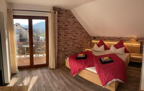 a bedroom with a bed with red pillows and a balcony at Pension Rieslingakademie in Mesenich