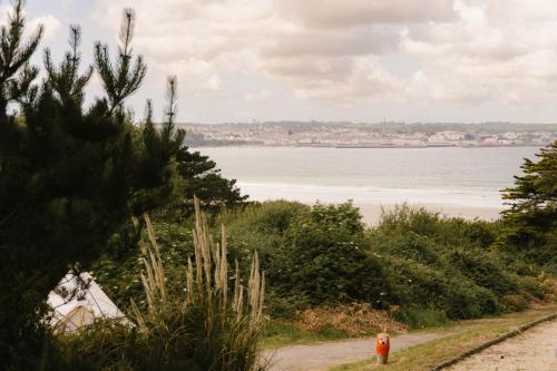 a view of the ocean from a hill with a tent at The Glamping Spot - Douarnenez in Plonévez-Porzay