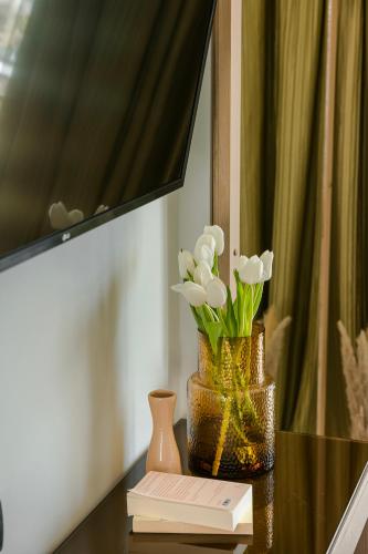 a table with a vase with flowers and a book at Alas Resort & Spa in Elia Laconias