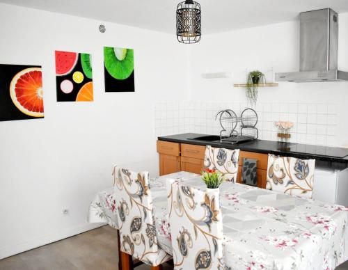 eine Küche mit einem Tisch mit Stühlen und Gemälden an der Wand in der Unterkunft Joli apartment proche du centre-ville in Poitiers