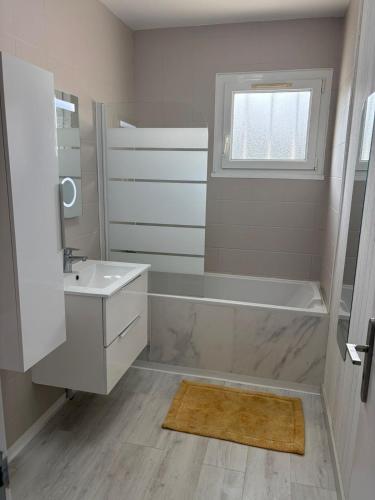 une salle de bain avec une baignoire, un lavabo et un miroir dans l'établissement Maison 3 chambres piscine, à Saint-Vincent-de-Tyrosse