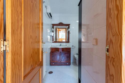 a bathroom with a sink and a toilet and a mirror at Villa con Jacuzzi exterior y Piscina cubiertos in Los Ángeles de San Rafael