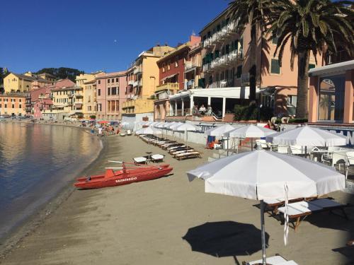 a beach with umbrellas and a red boat on the water at Hotel Miramare & Spa in Sestri Levante