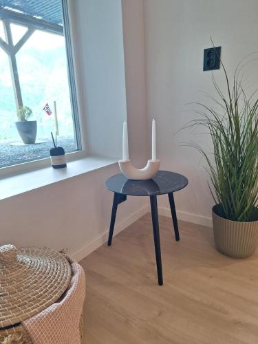 a table with a candle on it in a room with plants at Fjord Nest in Bergen