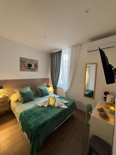 une chambre avec un lit avec une couverture verte dans l'établissement La Jade, à Narbonne