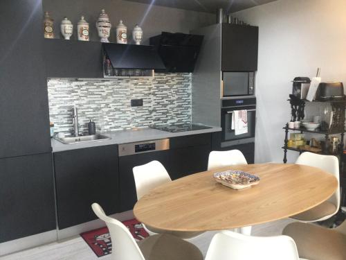 - une cuisine avec une table en bois et des chaises blanches dans l'établissement 3 chambres au coeur de biarritz, à Biarritz