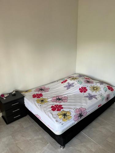a bed with a floral comforter and a night stand at Finca de Majo in Mocoa