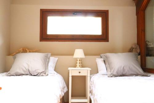 a bedroom with two beds with white sheets and a window at Cal Gano, 3-Story Stone & Wood Mountain Retreat in Llo
