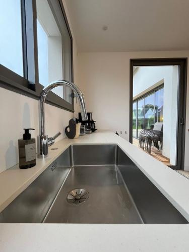 une cuisine avec un évier en acier inoxydable et une fenêtre dans l'établissement Maison Guelan Kerners, à Arzon