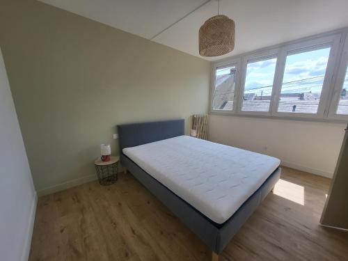 une chambre avec un lit dans une pièce avec deux fenêtres dans l'établissement Adamo, au Mans