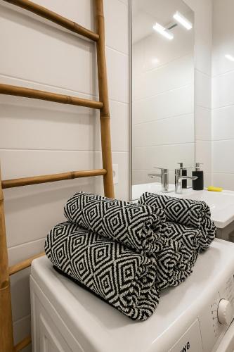 une salle de bain blanche avec une serviette noire et blanche dans l'établissement Le Cocon - Vue panoramique Strasbourg - Wifi - Netflix, à Strasbourg