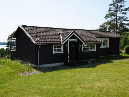 a small black house with a grassy yard at 5 person holiday home in MUNKEDAL in Munkedal