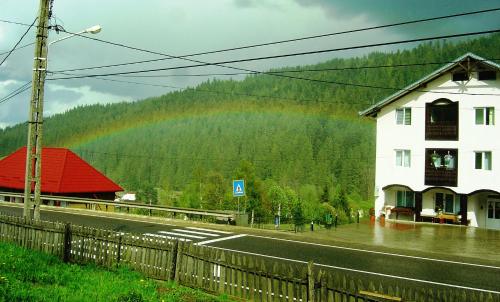 a rainbow over a building and a road with a house at Casa Lia in Valea Putnei
