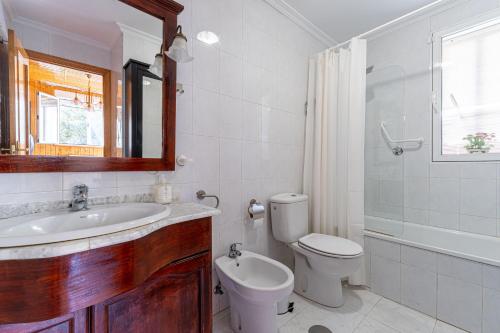 a bathroom with a sink and a toilet and a mirror at Villa con Jacuzzi exterior y Piscina cubiertos in Los Ángeles de San Rafael