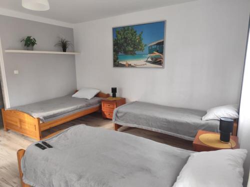 a room with three beds and a picture on the wall at Morska Fala in Sarbinowo