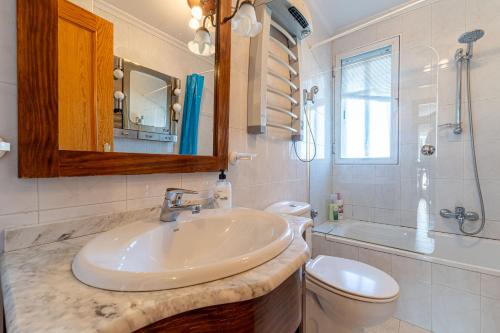 a bathroom with a sink and a toilet and a mirror at Villa con Jacuzzi exterior y Piscina cubiertos in Los Ángeles de San Rafael