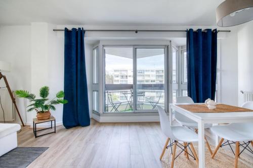 - un salon avec une table blanche et des rideaux bleus dans l'établissement Le Garenne au coeur de Vannes, à Vannes