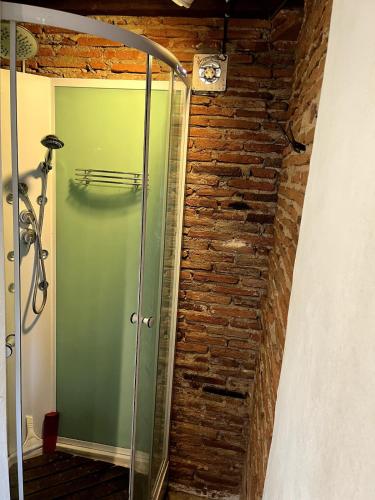 La salle de bains est pourvue d'une douche en verre et d'un mur en briques. dans l'établissement La Grange Cirque, à Uza