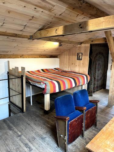 un lit et deux chaises bleues dans une pièce dans l'établissement La Grange Cirque, à Uza