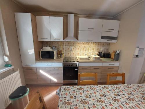 a kitchen with white cabinets and a table with chairs at Bodza apartman in Gyula