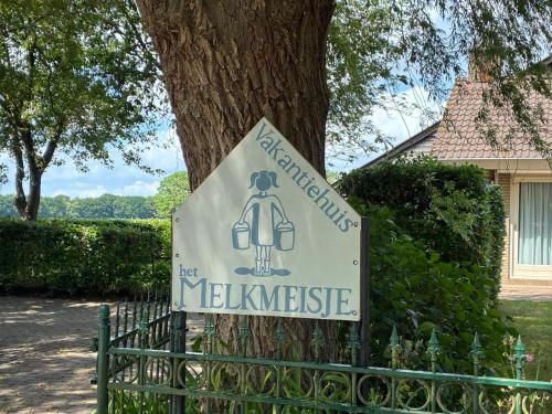 a sign on a fence in front of a tree at Vakantiehuisje Het Melkmeisje in Kaatsheuvel
