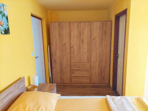 a bedroom with a wooden door in a yellow room at Bodza apartman in Gyula
