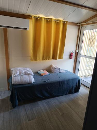 - un lit dans une chambre dotée d'un rideau jaune dans l'établissement CHALET SUR TERRAIN PRIVER, à Vias