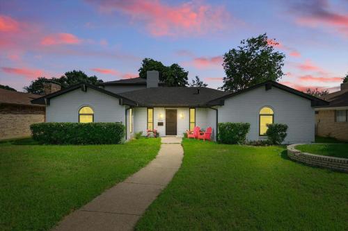 a white house with two red chairs in the yard at Spacious 5BR Getaway with Pool in Duncanville
