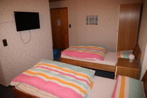 a room with two beds and a tv on the wall at Pension Central in Bad Endbach
