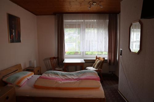 a bedroom with a bed and a desk and a window at Pension Central in Bad Endbach