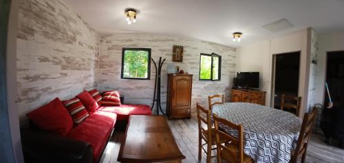 un salon avec un canapé rouge et une table dans l'établissement maison de campagne, à Saint-Aubin-de-Nabirat