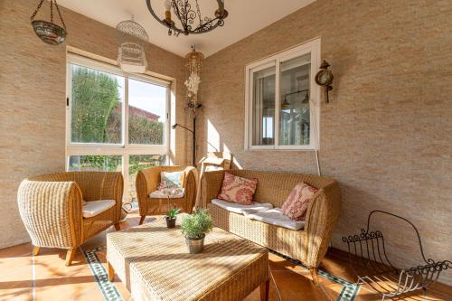 a living room with wicker chairs and a couch at Villa con Jacuzzi exterior y Piscina cubiertos in Los Ángeles de San Rafael