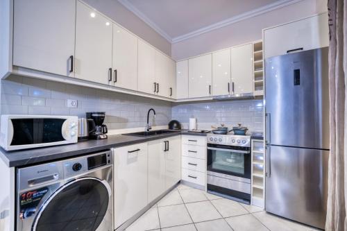 a kitchen with white cabinets and a stainless steel refrigerator at Villa Angela in Ágios Matthaíos