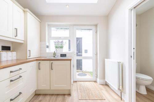 a white kitchen with a toilet and a window at Hillview House in Belfast