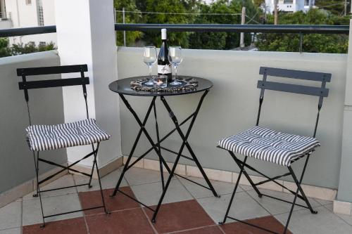 two chairs and a table with wine glasses on a balcony at Corinthian Green Villa in Vrahati