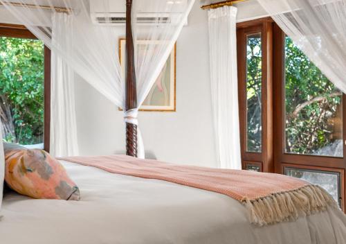 a bedroom with a bed with a canopy and windows at On The Rocks Villa in Spanish Town