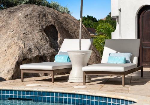 two chairs sitting next to a swimming pool at On The Rocks Villa in Spanish Town