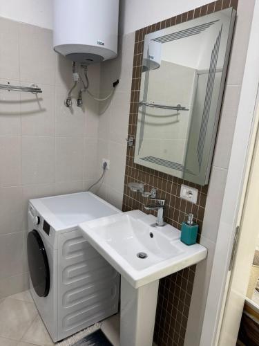 a bathroom with a sink and a washing machine at Eriksens Apartment in Pogradec