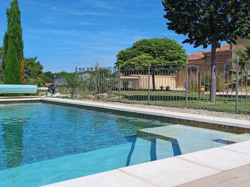 une piscine d'eau bleue en face d'une clôture dans l'établissement Gite 4 à 5 personnes sur domaine vinicole avec piscine chauffée - Vineyard cottage - heated pool, à Mormoiron