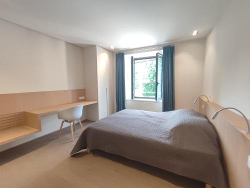 a bedroom with a bed and a desk and a window at Séjour d'exception au Moulin de la Vernède avec piscine, ruisseau, climatisation et parking in Conques-sur-Orbiel